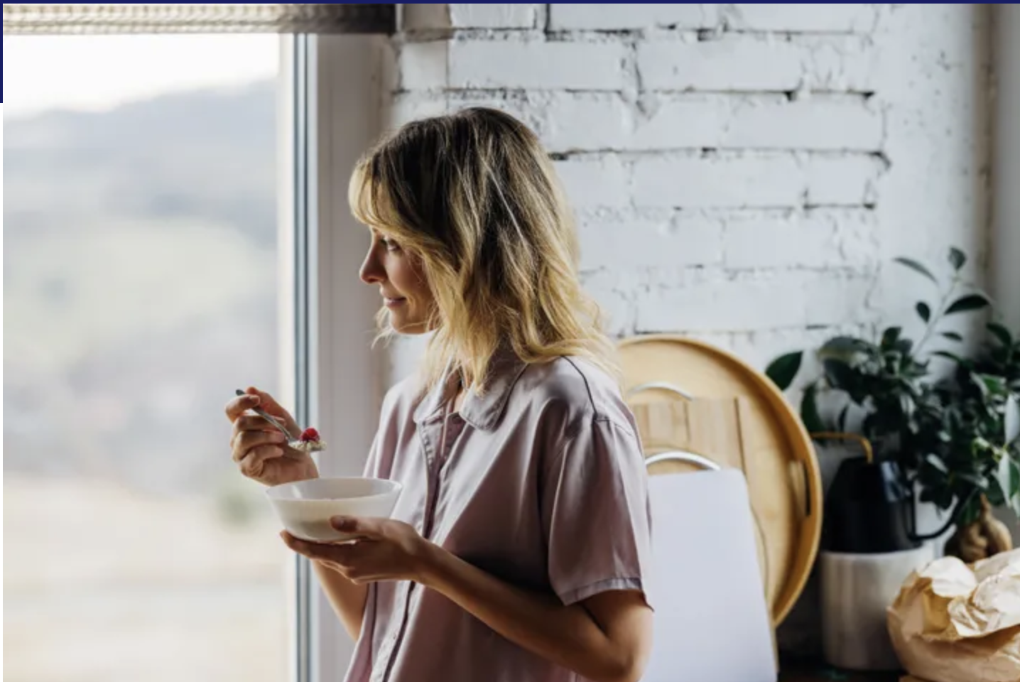 lady eating from a bowl by the window